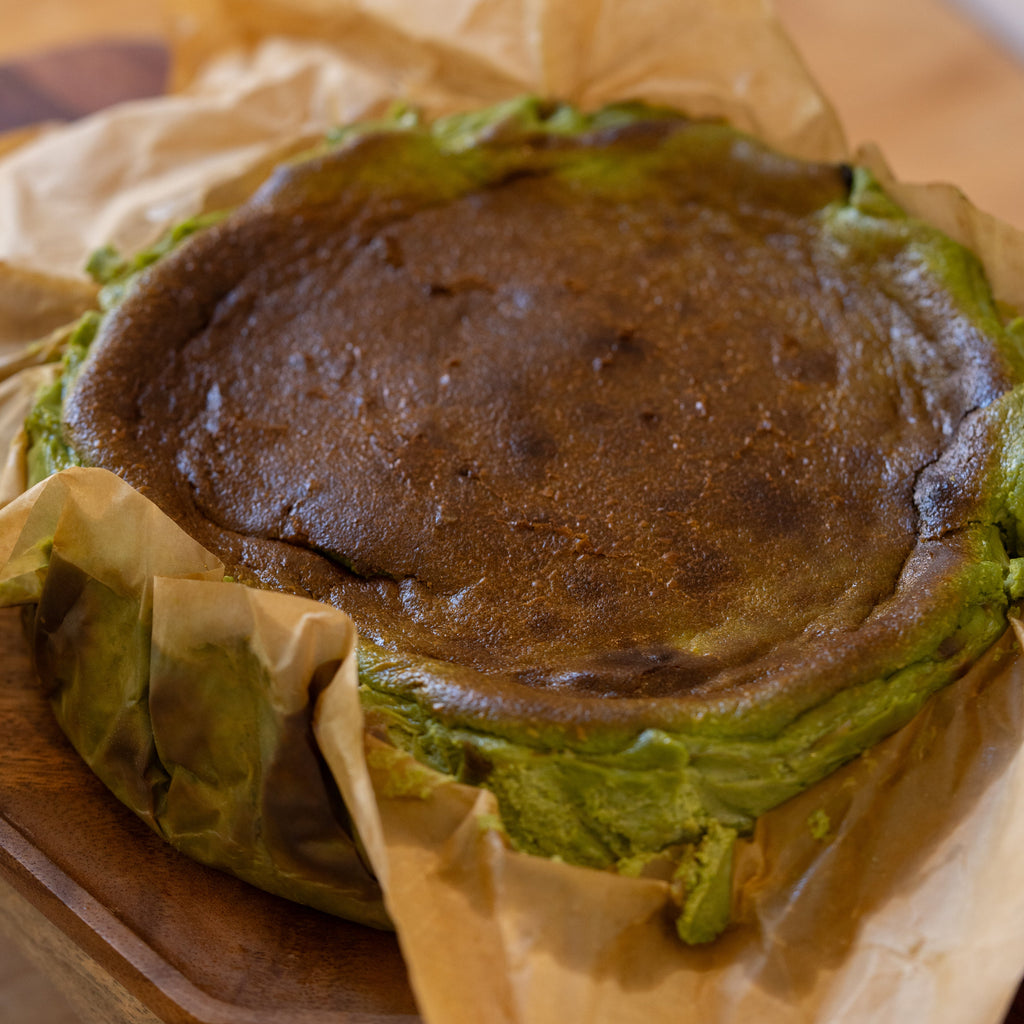 matcha basque cheesecake wrapped in brown paper on a wooden surface