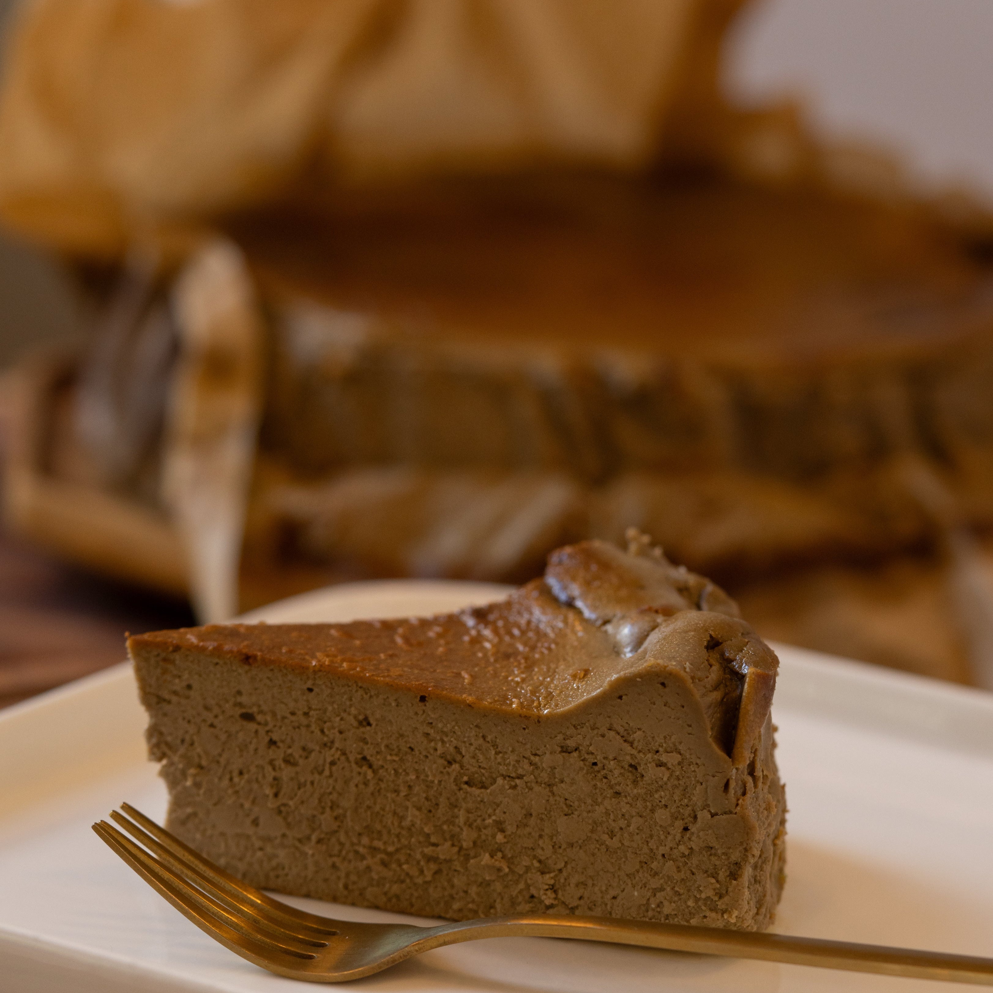 Slice of chocolate cake on a plate with a fork, blurred background