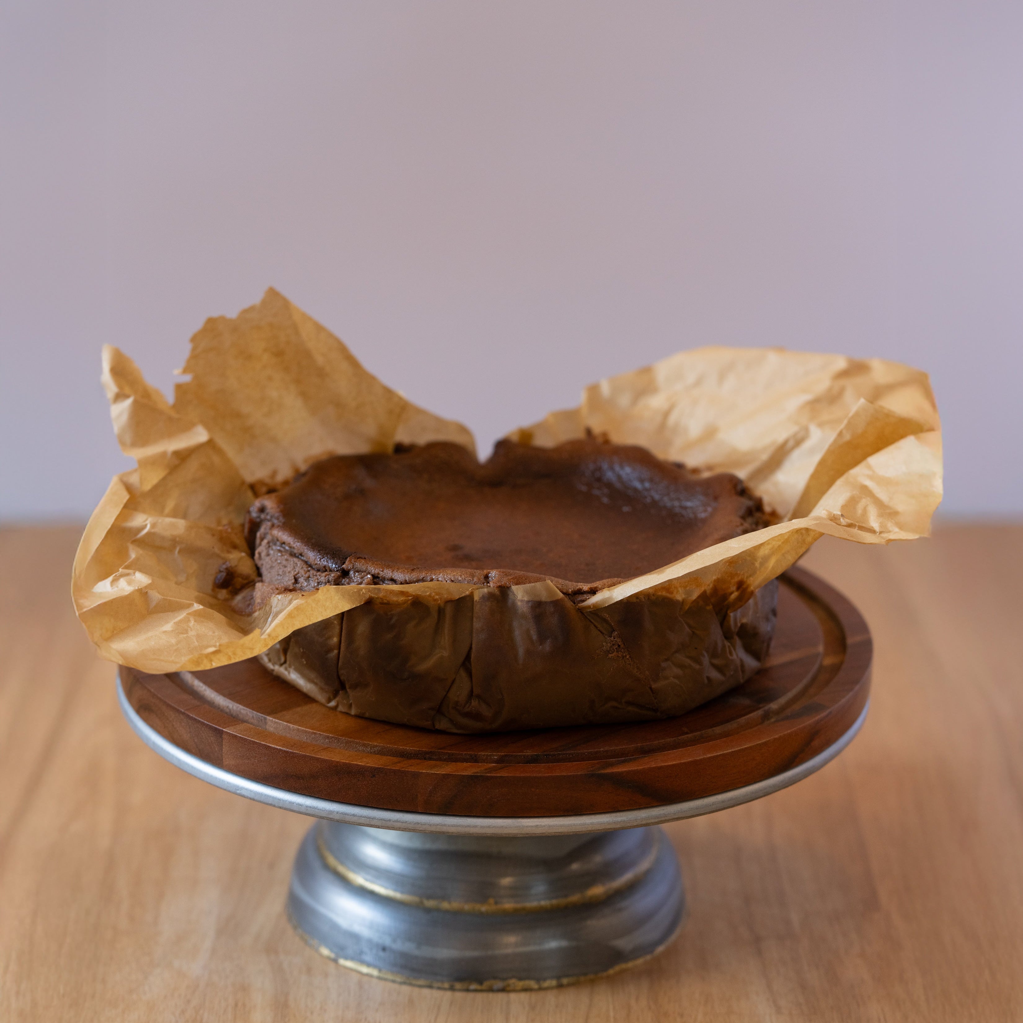 Chocolate dessert in a paper wrapper on a wooden stand with a plain background