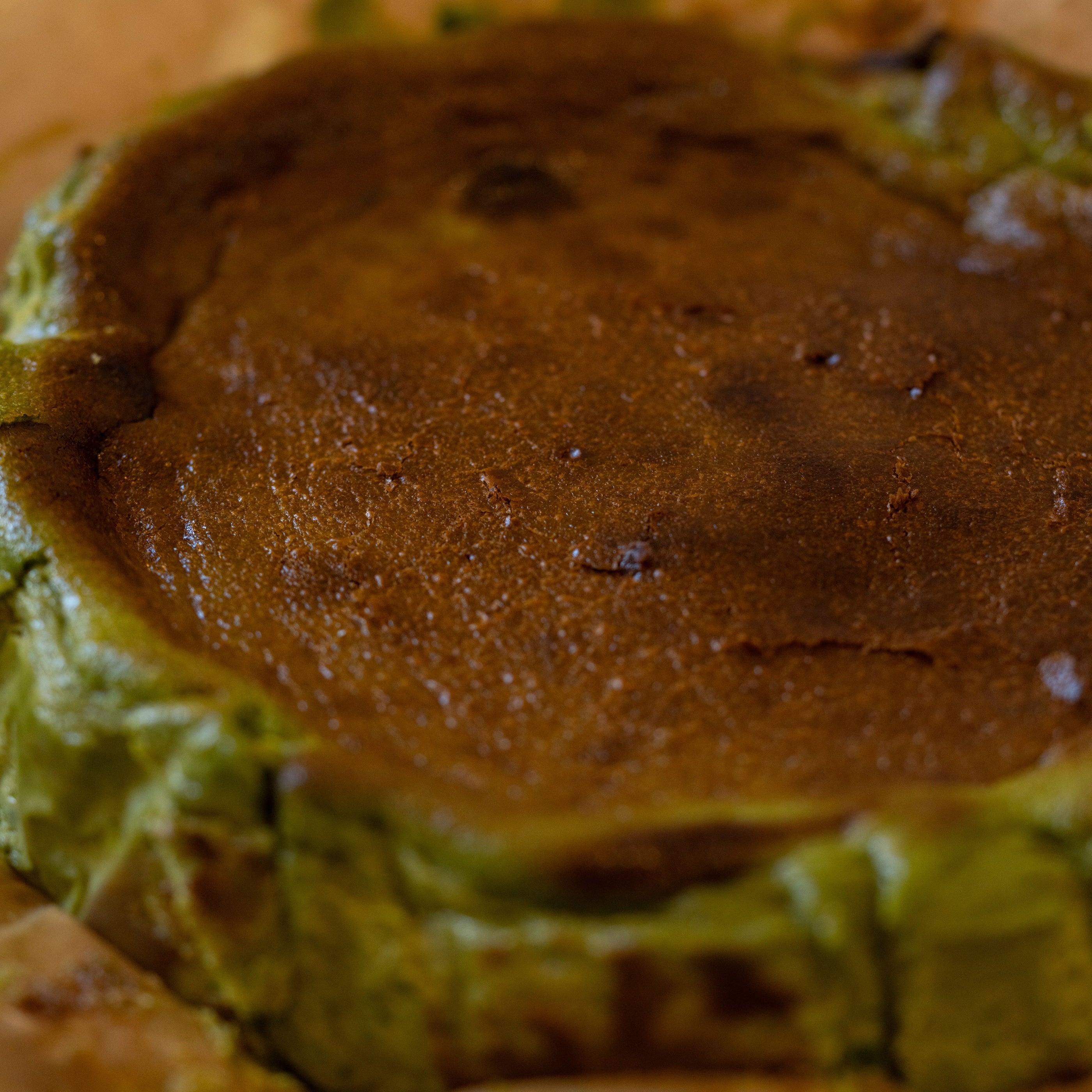 Close-up of a green and brown dessert, possibly a cheesecake or tart, with a crumbly texture.